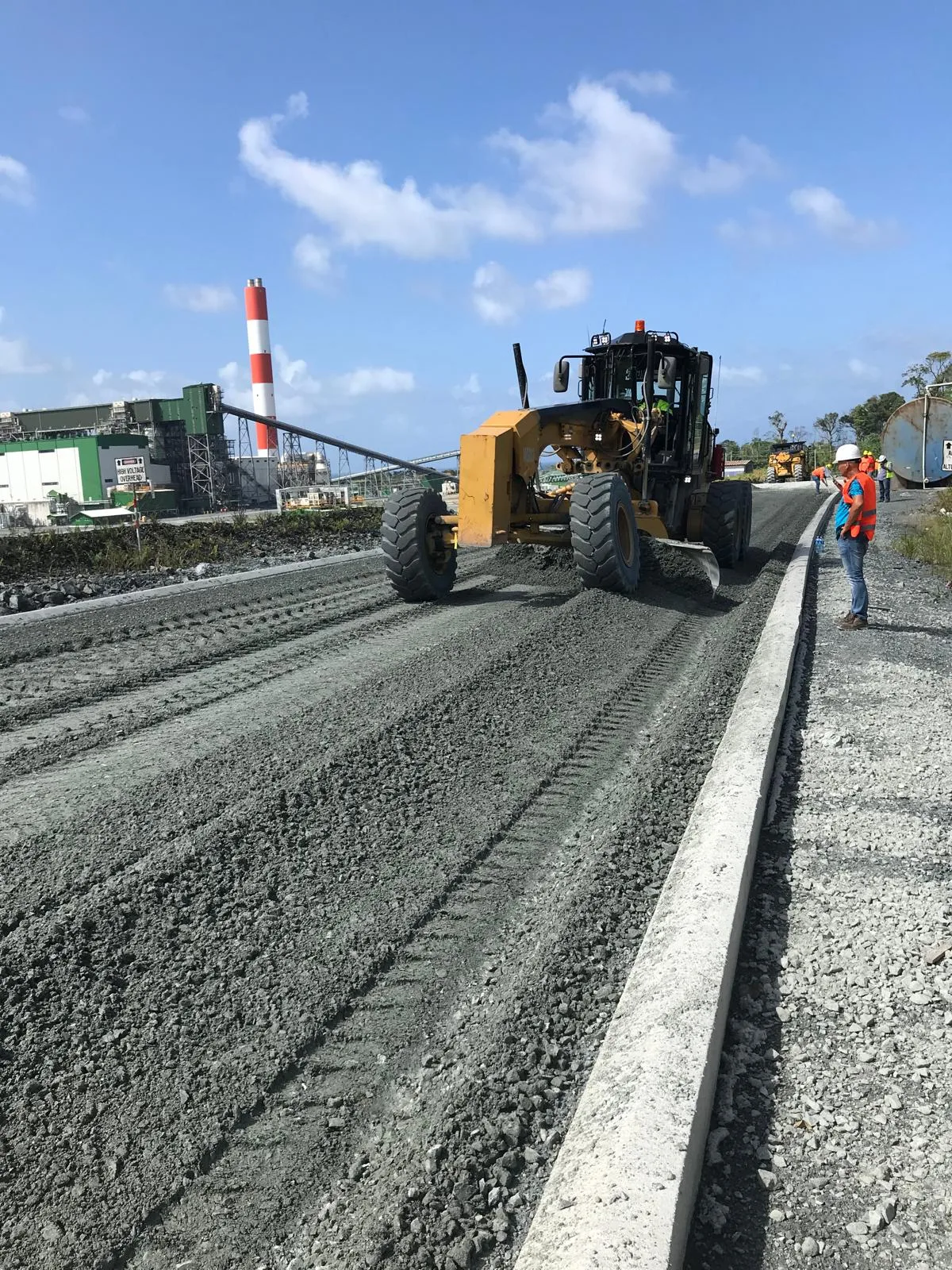 Grader shaping the treated surface for drainage