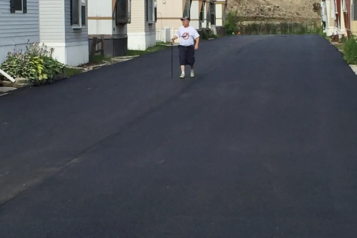 A community resident walking on a finished LL-TECH residential street — open to everyday traffic in hours, not weeks