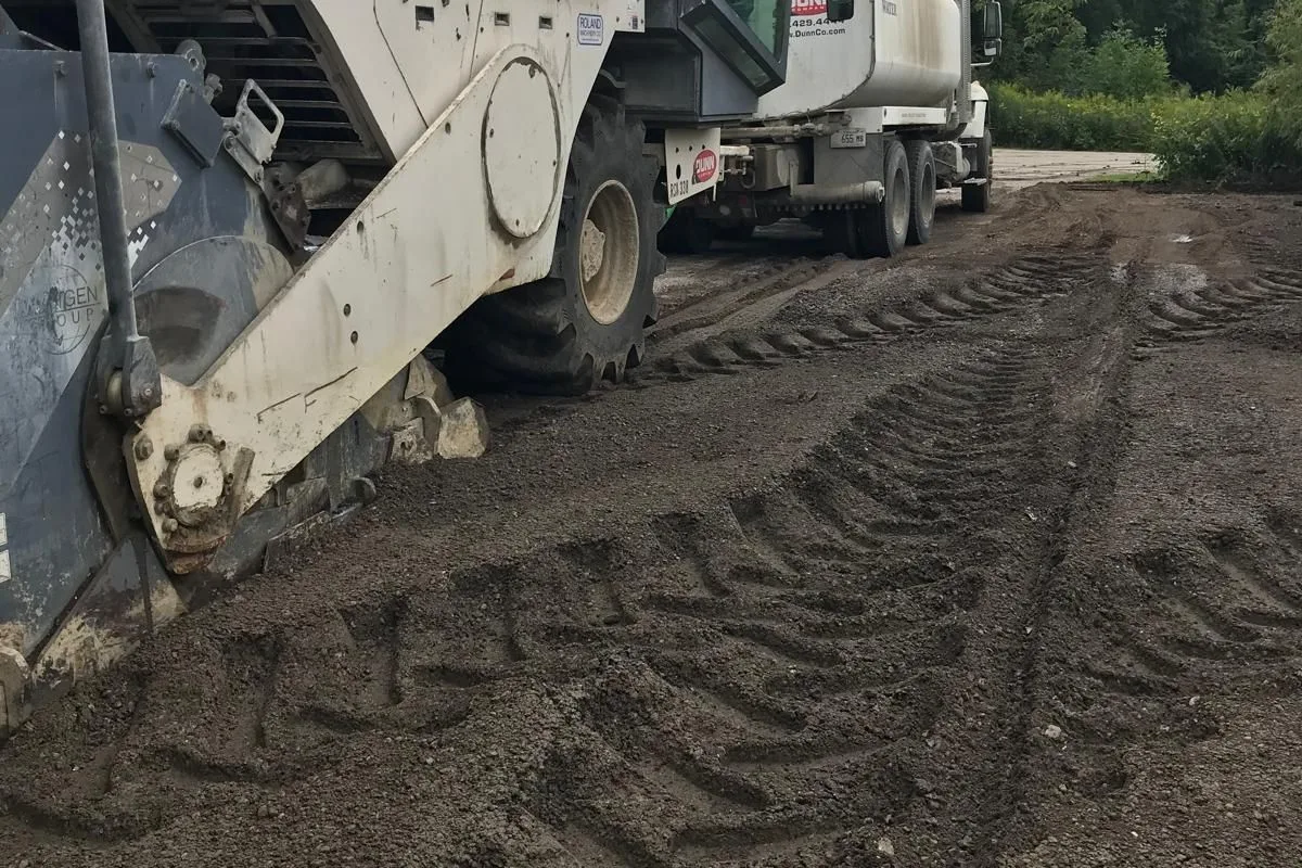 A standard contractor reclaimer (DUNN) and water truck on a community lot — equipment your contractors already operate, no specialized fleet